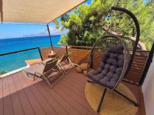 a porch with a wicker chair on a deck with the ocean at Vista Mare in Kámpos