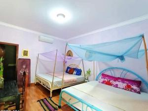a bedroom with two beds and a blue canopy at Monyharch Angkor Homestay, in Phumĭ Kngan Pông