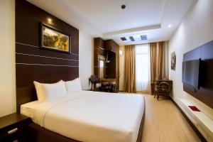 a hotel room with a large bed and a television at Eco Nest Signature Hotel in Hanoi