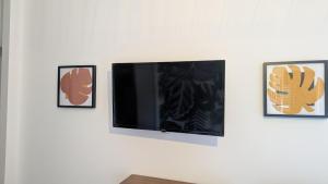 a flat screen tv hanging on a wall with three pictures at U Maestrale in Canale-di-Verde