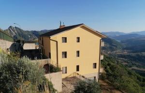 a house on a hill with mountains in the background at Il Nibbio Reale in Albano di Lucania