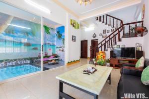 ein Wohnzimmer mit einem TV und einem Pool in der Unterkunft Biệt Thự Hồ Bơi VTU Bãi Sau in Vũng Tàu