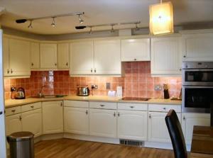 a kitchen with white cabinets and a stove at Sea Breeze Apartment near the Eden Project in St Austell