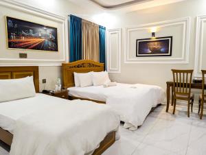 a hotel room with two beds and a desk at Hotel StayInn - Airport Branch Karachi in Karachi