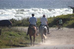 two people riding horses on a dirt road near the ocean at Posada del Corumbá in La Paloma