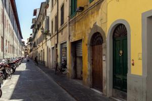 una calle estrecha con edificios con puertas verdes y motocicletas en Pinocchio House, en Florencia