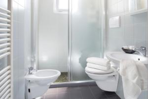 a white bathroom with a toilet and a sink at Club Meeting Hotel in Rimini +44 photos