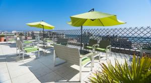 a patio with tables and chairs and an umbrella at Club Meeting Hotel in Rimini