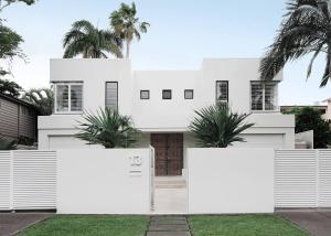 una casa blanca con palmeras delante en Elanda on Sunshine - Ocean views, see the whales, en Sunshine Beach