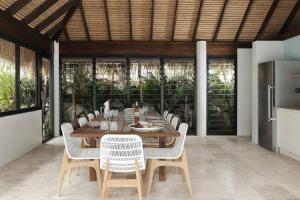 Un comedor con una mesa de madera y sillas blancas. en Elanda on Sunshine - Ocean views, see the whales, en Sunshine Beach