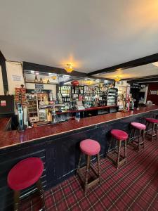a bar with red stools in front of a counter at OYO The Watermans Arms Hersham in Hersham