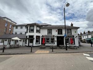 a white building with picnic tables in front of it at OYO The Watermans Arms Hersham in Hersham