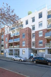 Dos coches aparcados delante de un edificio en 104 EastPerth Euphoria Escape 2BR Parkng, en Perth