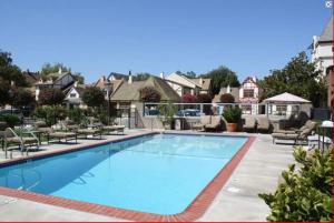 a large blue swimming pool in a yard with houses at Royal Copenhagen Inn in Solvang