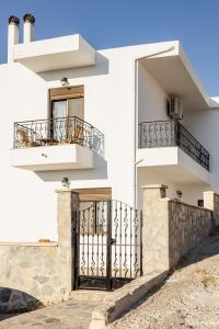 a white building with a gate and balcony at Gina's house in Asklipiḯon