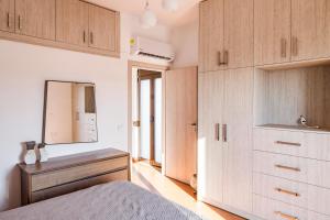 a bedroom with a bed and a mirror and cabinets at Gina's house in Asklipiḯon