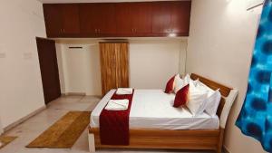 Un dormitorio con una cama con sábanas blancas y almohadas rojas. en Ananya service apartments, en Chennai