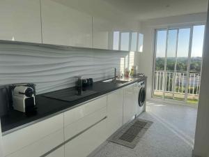 a white kitchen with a sink and a washing machine at Appartement vue imprenable à 10 mn à pied du vieux port in La Rochelle