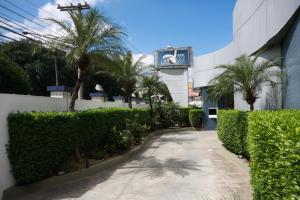 a walkway in front of a building with palm trees at Motel Golf (Adult Only) in Osasco
