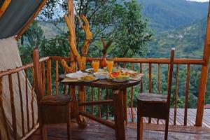 Una mesa con platos de comida en un balcón. en Ella Soul Nest Glamping Tent for Nature Lovers, en Ella