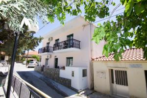 a white house with a balcony on a street at Limnos Family Studios in Angariónes