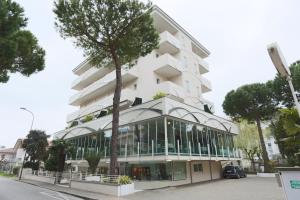 un edificio blanco con un árbol delante en Hotel Caribia Pinarella, en Cervia