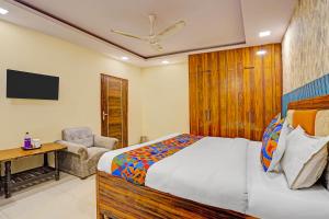 a bedroom with a bed and a chair and a television at Via Angel Pink Residency in Ghaziabad