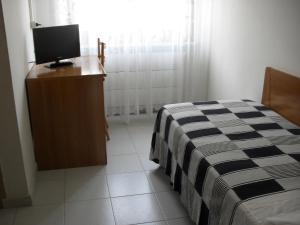 1 dormitorio con 1 cama y vestidor con TV en Al Caminetto, en Aosta