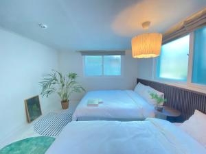 a bedroom with two beds and a potted plant at Stay in EV in Seoul