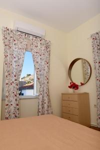 a bedroom with a window with a dresser and a mirror at Kalogiannis Apartments (AcquaBlue & SunnyShades) in Hydra