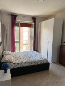 a bedroom with a bed and a large window at I colori della casa di Gio in Grugliasco