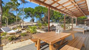 an outdoor patio with a wooden table and chairs at Cute Beach Cottage - Absolute Beach Front in Toukley