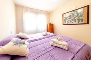 a bedroom with a large purple bed with towels on it at Casa Venerable Carabantes in Soria