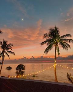 a view of a beach with palm trees and lights at Reef Beach Resort in General Luna