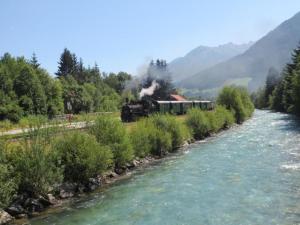 a train traveling down a river next to a river at Chalet in Königsleiten by Zillertal Ski Arena in Wald im Pinzgau
