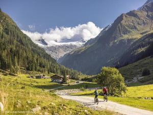 two people riding bikes down a road in the mountains at Chalet in Königsleiten by Zillertal Ski Arena in Wald im Pinzgau