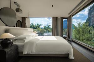 a bedroom with a white bed and a large window at YINGMAN HOTEL in Yangshuo