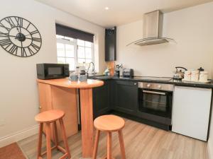a kitchen with a counter and two stools in it at Well Cottage in Malmesbury