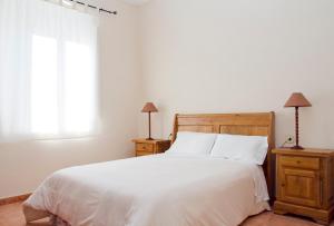 1 dormitorio con 1 cama blanca, 2 mesitas de noche y ventana en Holiday home Can Clerc, en Osor