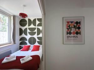 una camera da letto con due letti con cuscini rossi di Le Seventy's, T3 vintage avec jardin a Lons Altre 5 foto