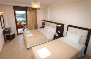 a hotel room with two beds and a balcony at Pelagos in Parga