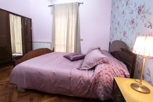 Un dormitorio con una cama con sábanas moradas y una lámpara. en Casale Godenza, en Matelica