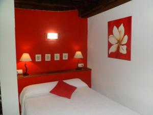 Dormitorio rojo con cama blanca y pared roja en Alborada, en Sequeros