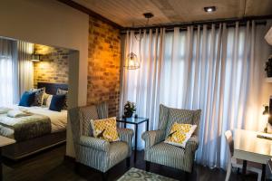 a bedroom with a bed and two chairs at Grey Manor Guesthouse in Potchefstroom +35 photos