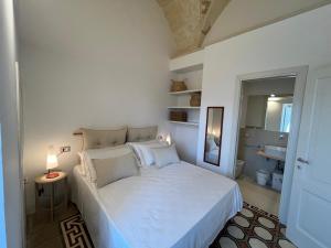a bedroom with a white bed and a mirror at La Torretta dimora storica in Montesano Salentino