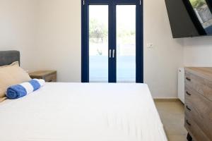 a bedroom with a white bed and a sliding glass door at Ifigenia VIlla Sissi in Sissi