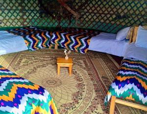 a room with two beds and a table in a yurt at Aidar Yurt Camp in Taldy