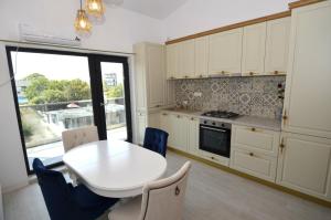 una cocina con una mesa y sillas blancas y una ventana en Daren Apartment, en Eforie Nord 13 fotos más