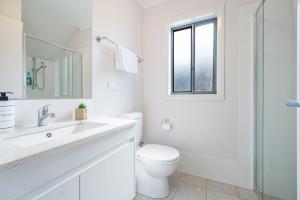 a white bathroom with a toilet and a sink at Warm cozy 5Br house near train station & Coles in Leppington +14 photos