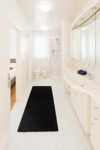 a white bathroom with a shower and a black rug at Stilvolle, gemütliche und haustierfreundliche Wohnung in Hackenheim +5 photos